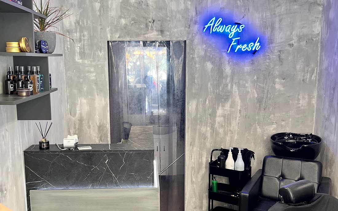 Το εσωτερικό του Hykos hair studio, ο τσιμεντένιος τοίχος με το μπλε νέον Always Fresh και ο πάγκος από μαύρο μάρμαρο